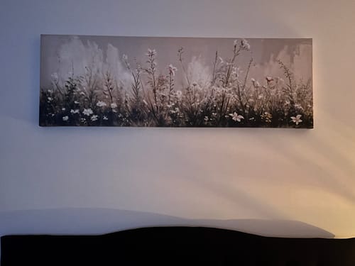 Reviewer's Flower Field Wall Art hanging on a bedroom wall above their bed's headboard.