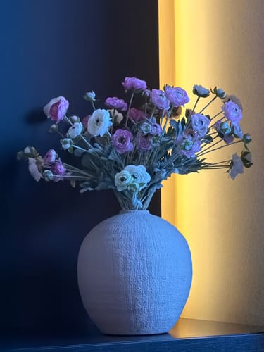 Recensent toont het Ranonkel Arrangement met roze en witte bloemen in een lichte, ronde vaas.