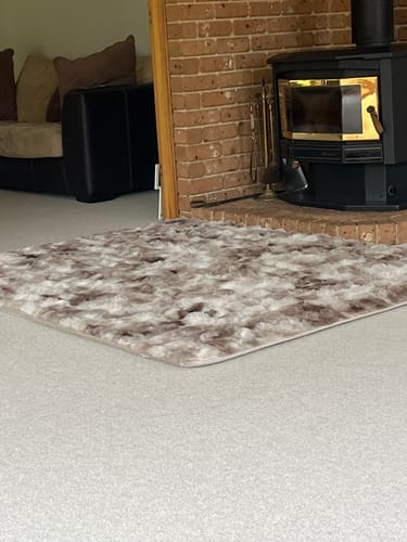 Reviewer's Snow Mink Mellow Mat in a living room, placed on the carpet near a fireplace.