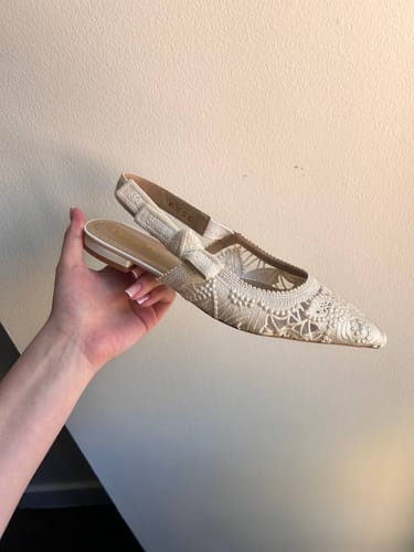 Customer holding a white J'Adior Slingback Flat, showing the detailed mesh fabric and bow.