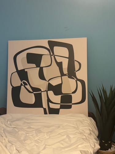 Customer's Harmony in Motion canvas art propped on a bed with white bedding, against a light blue wall.