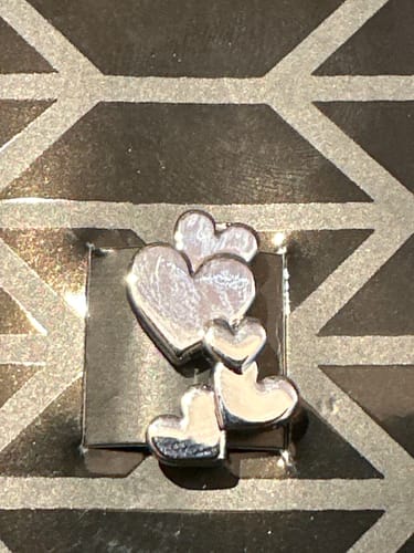 Customer's shiny silver Hearts Charm, a cluster of small hearts, on its packaging.