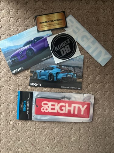 Customer's red 80Eighty Smoke Ice Air Freshener in its packaging, shown with several branded stickers and postcards.