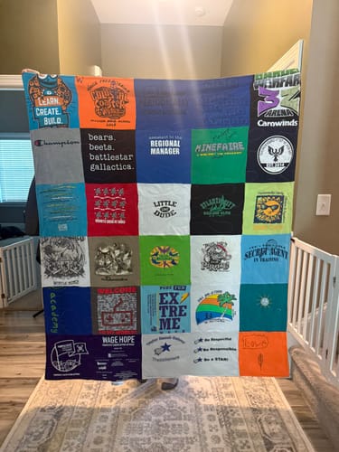 Reviewer holding up their large, colorful Premium T-Shirt Quilt made from various t-shirts.