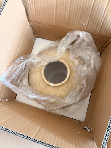 Recensent toont de pot voor het Wax Arrangement in de verzenddoos, die volgens de review beschadigd was.
