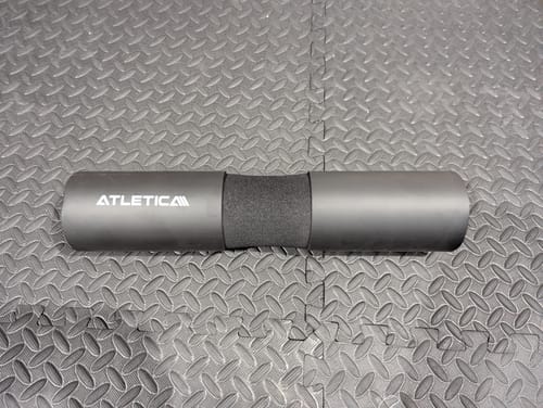 Kundenrezension: Das schwarze Langhantel-Nackenpolster von Atletica liegt auf einer strukturierten Fitnessmatte.