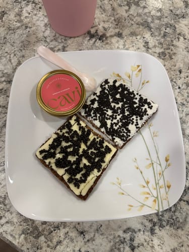 Customer's Siberian Sturgeon Caviar on toasted bread, one piece with butter and one with cream cheese.