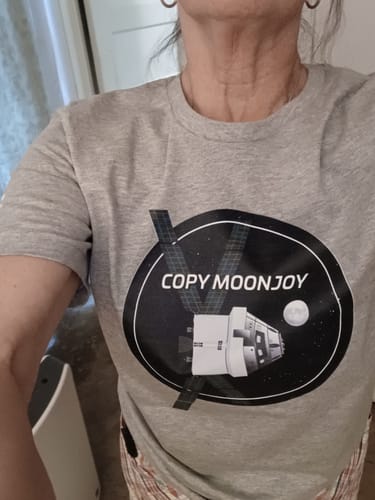 A reviewer wearing the grey Copy Moonjoy T-shirt, showing a close-up of the front graphic with a spacecraft.