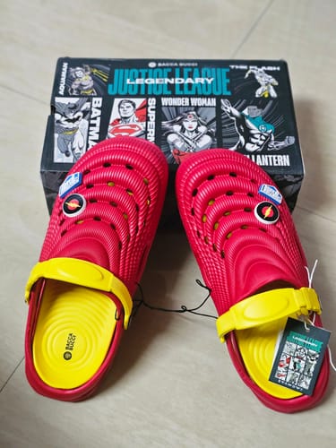 Customer's red and yellow Justice League PowerGrip Clogs with Flash badges, shown in front of the product box.