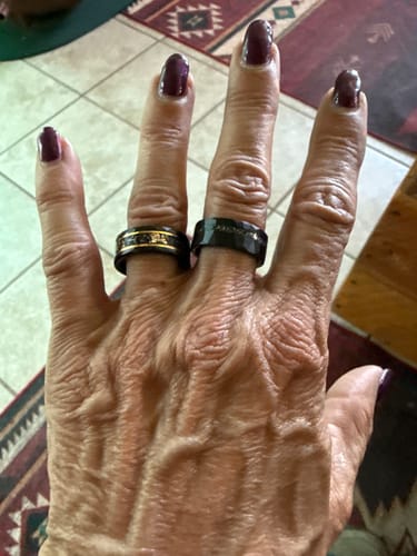 Customer's hand showing two Titanfall rings, a black hammered ring and one with gold flake inlay.