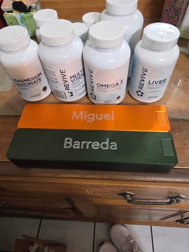 Customer's personalized orange and green Weekly AM-PM Vitamin XL Cases on a wooden dresser with supplement bottles in the background.