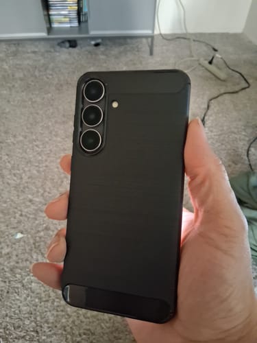 Reviewer's hand holding a Samsung Galaxy S25 FE in the black Venture Series case.