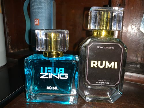Customer's Bleu De Zing and Rumi fragrance bottles sitting side-by-side on a wooden surface.
