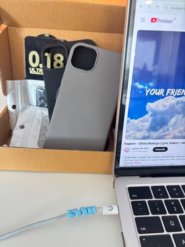 Reviewer unboxing the Graphite Grey Signature Leather Magsafe Case, with a black case and accessories in the box.