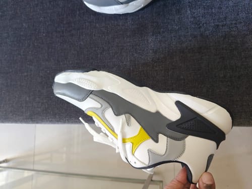 Customer holding a white, grey, and yellow Bacca Bucci Spark shoe to show the unique side design.