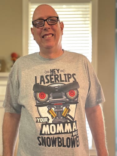 Reviewer smiling while wearing the grey Your Momma Was A Snowblower Short Circuit T-Shirt.