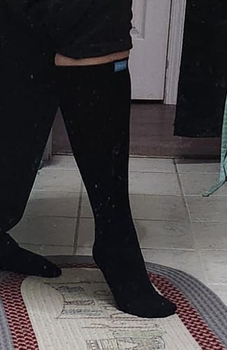 Reviewer wearing the black knee-high Performance Eucalyptus Compression Socks on their leg.