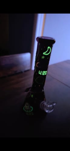 Customer's Beam Me Up Beaker Bong glowing in a dark room, highlighting its green cosmic designs and 4:20.