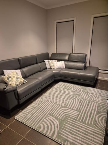 Customer's Mellow Mat Arcade print rug in their living room, placed in front of a large grey couch.
