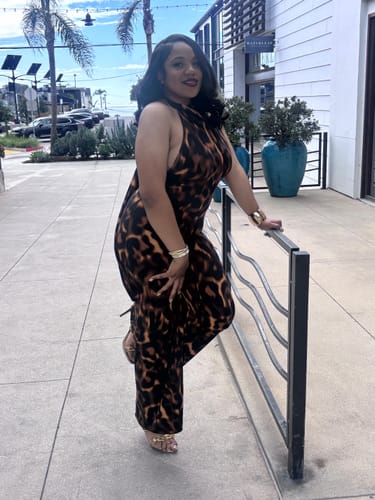 Reviewer posing outdoors in the leopard print Naked Print Halter Wide Leg Jumpsuit.