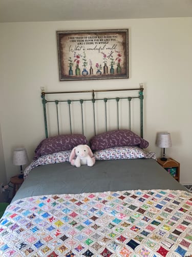 Customer's What A Wonderful World Sign displayed on the wall above a bed in a guest room.