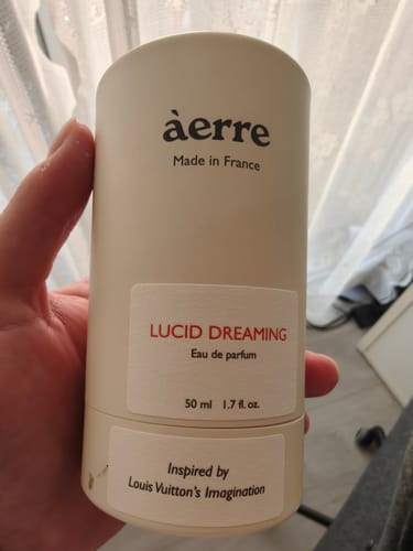 Reviewer holding the white tube of Lucid Dreaming eau de parfum.
