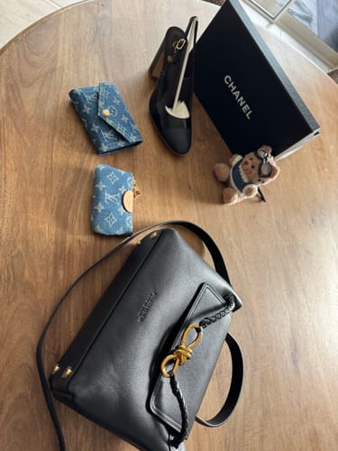 Customer's LV Beige Blue Bear Charm displayed on a wooden table among other accessories.