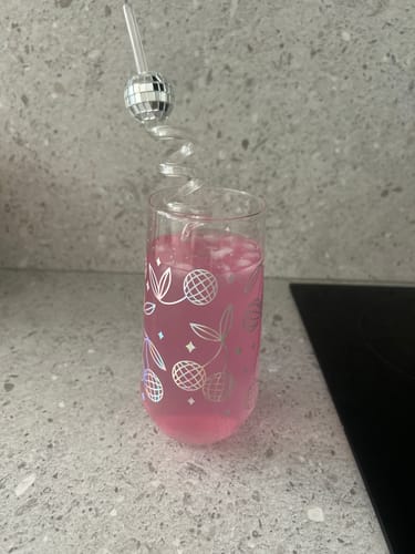 Customer's Strawberry Watermelon drink in a decorative glass with ice and a fun, disco ball straw on a kitchen counter.