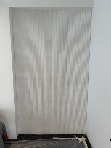 Customer's installed Round line stone wall panel, showing its textured vertical lines in a room.