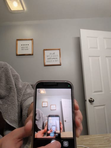 Customer showing the screen protector's crisp display on a phone, creating an infinity mirror effect.