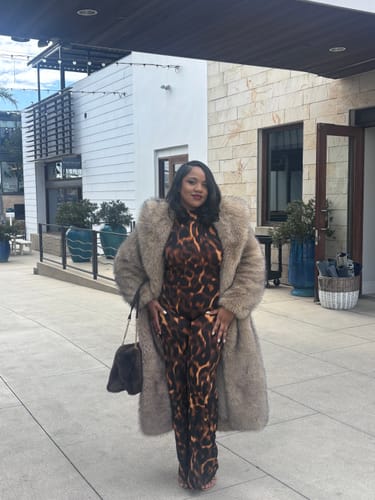 Customer wearing the Naked Print Halter Jumpsuit styled with a long, fluffy coat outdoors.