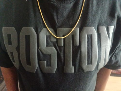 Close-up of a customer wearing the Golden Charismatic Chain over a black graphic t-shirt.
