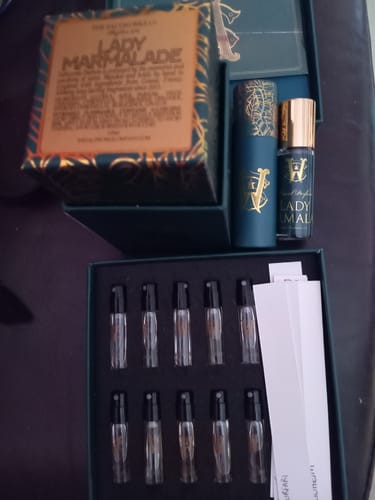 Customer's Lady Marmalade perfume, shown with its box, a travel bottle, and a discovery set of fragrance samples.