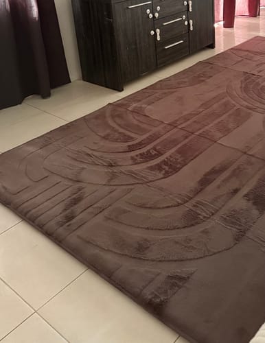 Customer's mocha-colored Mellow Mat with a carved pattern laid out on a tiled floor in a living room.