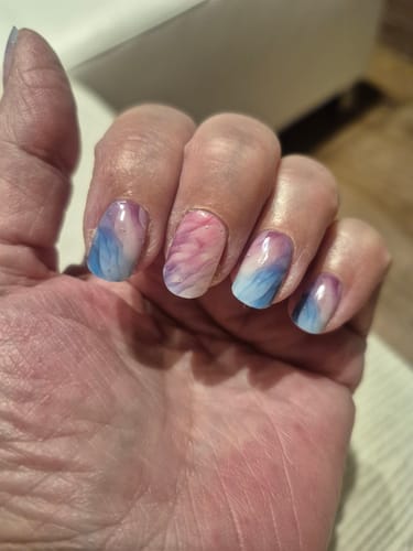 Hand einer Rezensentin mit glänzenden 'Pastel Waves' UV Gel Folien, die ein pastellfarbenes Wellenmuster zeigen.