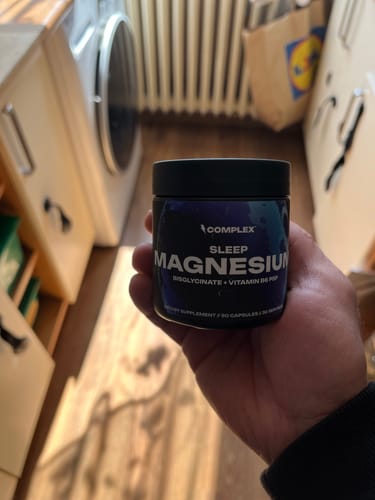 A reviewer holding the black jar of Sleep Magnesium in their hand.