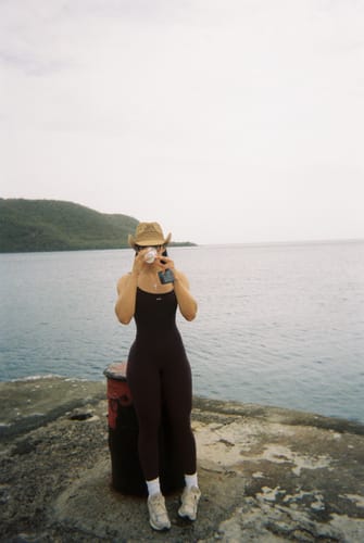 Reviewer wearing the form-fitting Espresso Onesie outdoors by the water.