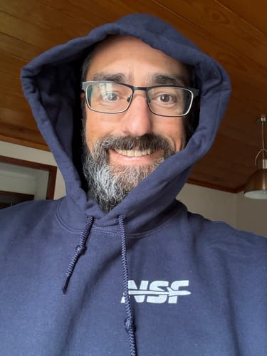 Close-up of a reviewer smiling while wearing the navy Artemis II - Unisex Hoodie with the hood up.