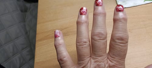 Nahaufnahme der Hand einer Kundin, die die 'Pink Mermaids' Nagelfolien auf ihren Fingernägeln trägt.