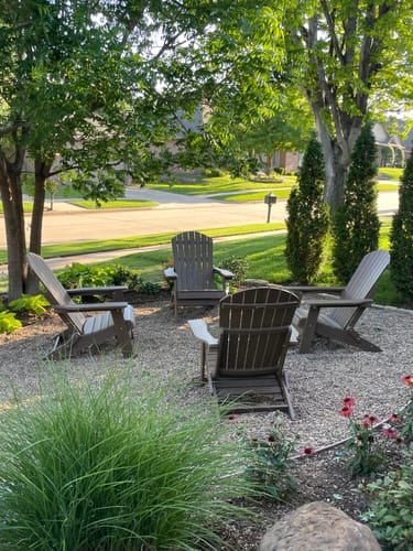 Customer's four brown Adirondack chairs arranged in a circle in their landscaped front yard.