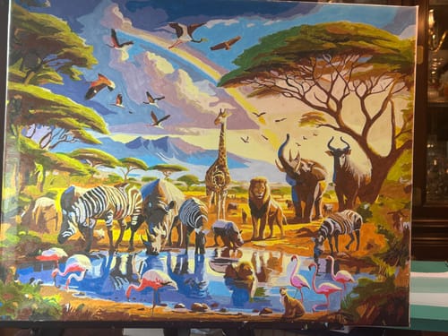 Reviewer's completed Wild Animals Paint by Numbers kit, showing a colorful safari scene with various animals at a watering hole.