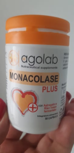 Recensore tiene in mano il flacone bianco di integratori Monacolase Plus con un tappo arancione.