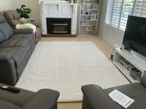 Customer's large Vanilla Cream Mellow Mat with a carved design, laid out in a living room between two sofas.