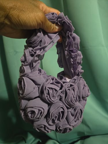 Reviewer holding the purple Roses Mini Handbag, showing its small size and rosey texture.