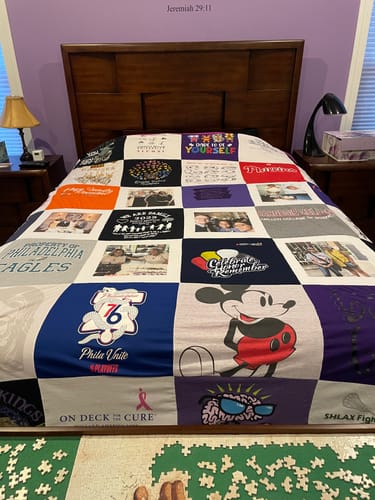 Customer's custom Project Repat T-Shirt Quilt, made with t-shirts and photos, spread on a bed.