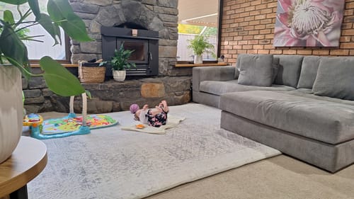 Customer's Silver Mist Mellow Mat in a living room with a baby lying on the soft, patterned surface.