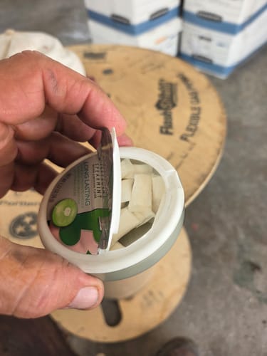 Reviewer's hand holding a repurposed mint tin filled with Mountain Wintergreen Nicotine Pouches.