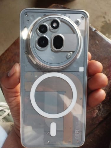 Reviewer holding a Nothing phone in the transparent Magsafe case, showing the camera and white magnet ring.