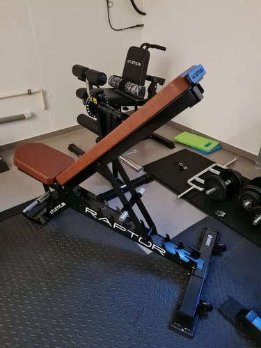 Kundenfoto der Raptor Hantelbank mit braunem PU-Leder, schräg gestellt in einem Heim-Fitnessstudio.