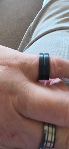 Close-up of a customer's hand wearing the black Stratus ring with its vivid blue groove.